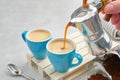 Coffee pouring in cups from Italian coffee espresso maker. Two coffee mugs and moka coffee pot