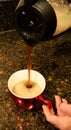 Coffee pouring from coffee pot into red cup
