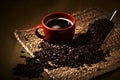 Coffee in Red cup with coffee Beans on table cloth Royalty Free Stock Photo