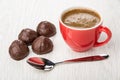 Coffee in red cup, spoon, few chocolate candy on table Royalty Free Stock Photo