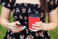 Coffee in a red plastic glass. Smartphone in female hands. The concept of a lifestyle, a break and communication on the Internet