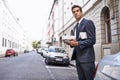 On a coffee run. A handsome businessman in s suit standing with his coffee and newspaper in a city street. Royalty Free Stock Photo