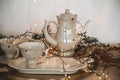 Coffee service. Vintage Teapot and cups decorated with Christmas tree branches and a glowing garland