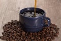 Coffee serving over a blue cup, with coffee beans around it