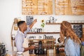 Coffee shop, customer and barista with pointing at menu for purchase, decision and service at restaurant. Waiter, small Royalty Free Stock Photo