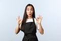 Coffee shop, small business and startup concept. Excited vietnamese barista, female cafe staff in black apron showing