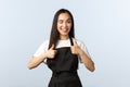 Coffee shop, small business and startup concept. Friendly cheeky asian girl in black apron working as barista at cafe or Royalty Free Stock Photo