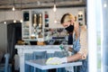 Coffee shop woman owner working with face mask and gloves, disinfecting tables.