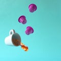 Coffee spilling out of a floating cup with three magenta colour coffee machine capsules Royalty Free Stock Photo