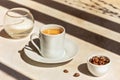 Coffee still life with cup of espresso, coffee beans, sugar and long dark shadows Royalty Free Stock Photo