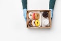 Coffee with sweets for two takeaway during covid outbreak. Waiter in rubber gloves gives box of donuts with glaze and