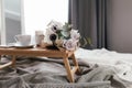 Coffee table on bed. Flowers, coffee cup and candles. Interior gray tones, plaid Royalty Free Stock Photo