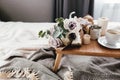 Coffee table on bed. Flowers, coffee cup and candles. Interior gray tones, plaid Royalty Free Stock Photo