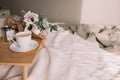 Coffee table on bed. Flowers, coffee cup and candles. Interior gray tones, plaid Royalty Free Stock Photo