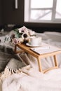 Coffee table on bed. Flowers, cup, candles, note pad, pen. Gray interior, plaid Royalty Free Stock Photo