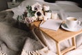 Coffee table on bed. Flowers, cup, candles, note pad, pen. Gray interior, plaid Royalty Free Stock Photo