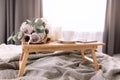 Coffee table on bed. Flowers, cup, candles, note pad, pen. Gray interior, plaid Royalty Free Stock Photo