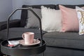 Coffee table with cup of tea, near dark gray sofa with pillows in a living room Royalty Free Stock Photo