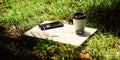 Coffee take away. Laptop modern smartphone with earphones and coffee cup on green grass. Remote job. Coffee break Royalty Free Stock Photo