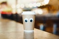 Coffee takeaway cup with cartoon eyes in cafe. Concept of hospitable cafe Royalty Free Stock Photo