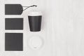 Coffee takeaway set mockup for brand - black paper cup, blank card, label, white cap on white wood board, copy space, top view.