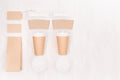 Coffee takeaway set mockup for brand - two brown paper cups with blank card, label, packet, cap, sugar, copy space on white wood. Royalty Free Stock Photo