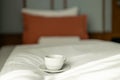 Coffee or tea cup on the bed. Hotel room or bedroom Interior, morning time. Concept of easy breakfast. One white ceramic Royalty Free Stock Photo