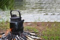 Coffee or tea in a kettle on a fire in the forest by the lake in the afternoon. Travel and camping concept Royalty Free Stock Photo