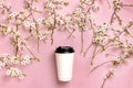 Coffee or tea paper cup and spring branches of white flowers of cherry on pink background top view flat lay. Take away coffee cup Royalty Free Stock Photo