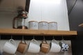 Coffee, tea, and sugar boxes with cups in a kitchen rack