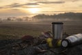 Coffee in a thermos on logs at sunrise Royalty Free Stock Photo