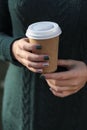 Coffee to go cup holding woman`s hand in autumn park