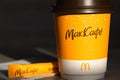 Coffee to go of McDonald`s with the inscription Maccafe in Russian stick with sugar on the table with a napkin and a straw. Fast Royalty Free Stock Photo