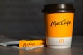 Coffee to go of McDonald`s with the inscription Maccafe in Russian stick with sugar on the table with a napkin and a straw. Fast Royalty Free Stock Photo