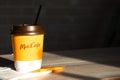 Coffee to go of McDonald`s with the inscription Maccafe in Russian stick with sugar on the table with a napkin and a straw. Fast Royalty Free Stock Photo