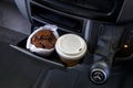 Coffee to go and a muffin in cupholder of a car