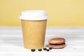 Coffee to go in paper eco cup with chocolate french macaroon on wooden and light orange background, Fast food, Copyspace