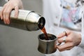 Coffee in travel. Girl pouring hot black coffee from thermos outdoor. Close up Royalty Free Stock Photo