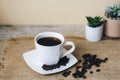 Coffee in white cup and coffee beans on sackcloth napkin. Selective focus Royalty Free Stock Photo
