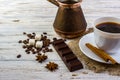 Coffee in a white cup on a small plate on sacking and cinnamon sticks. Coffee beans, pieces of sugar, anise and a chocolate bar on Royalty Free Stock Photo