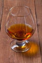 Cognac in a glass goblet on the old wooden table