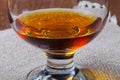 Cognac in a glass goblet on the old wooden table and linen napkin. Selective focus