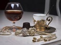 Cognac in tulip-shaped glass, jewelry and golden coffee cup on table, luxurious elegance style Royalty Free Stock Photo