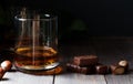 Cognac or whisky or brandy in a glass. Pieces of chocolate and hazelnuts. Dark background. Copy space Royalty Free Stock Photo