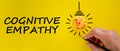 Cognitive empathy symbol. Male hand with black pencil, light bulb icon. Words `cognitive empathy`. Beautiful yellow background.