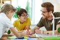 Laughing short-haired man in clear glasses helping little boys Royalty Free Stock Photo