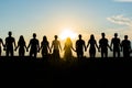 Cohesion concept. Black silhouettes of friends holding hands stands at sunset. Royalty Free Stock Photo