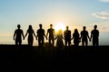 Cohesion concept. Black silhouettes of friends holding hands stands at sunset. Royalty Free Stock Photo