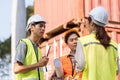Logistics engineering team strategizing project details at a construction site with blueprints and tools
