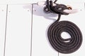 Coil of black, nylon, 3 4 inch dock line, tied to metal cleat, wood dock